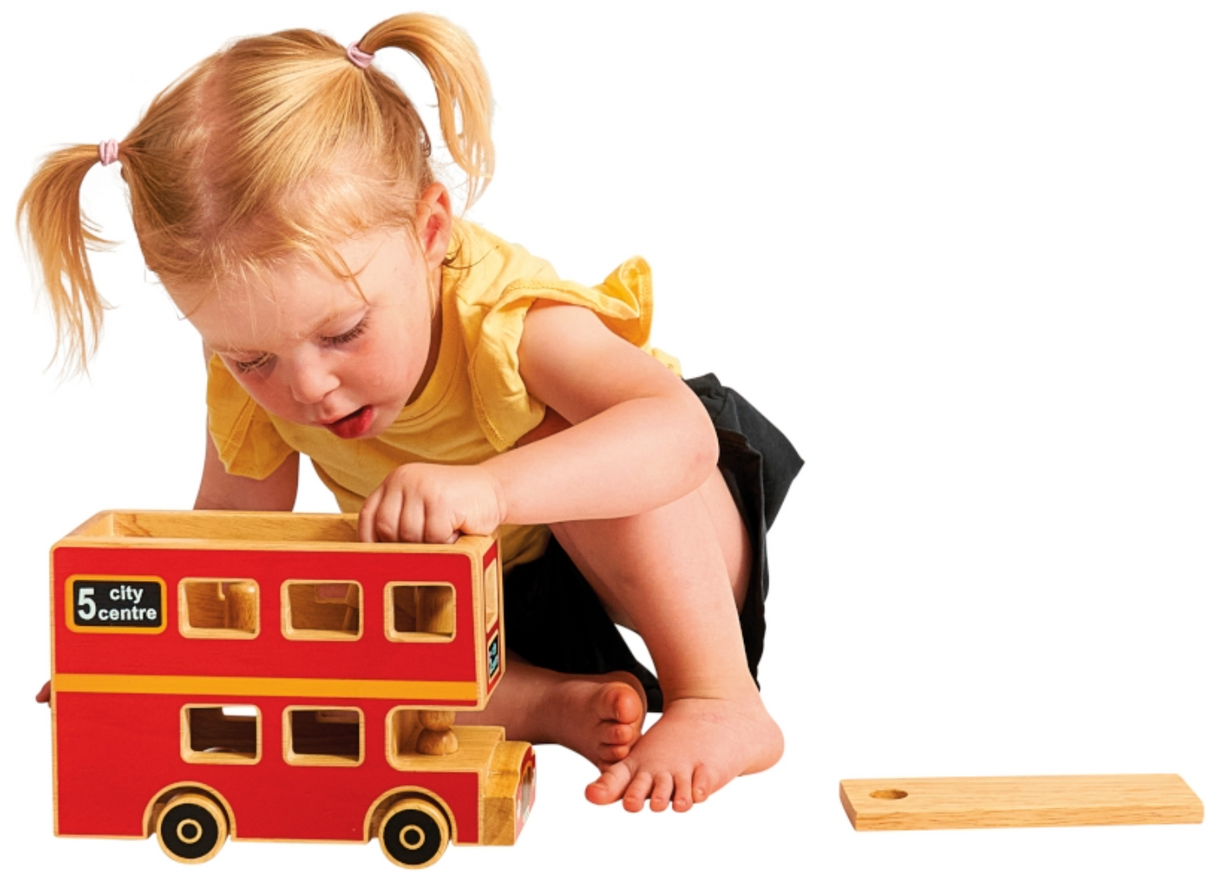 Child playing with a wooden toy bus on a white background