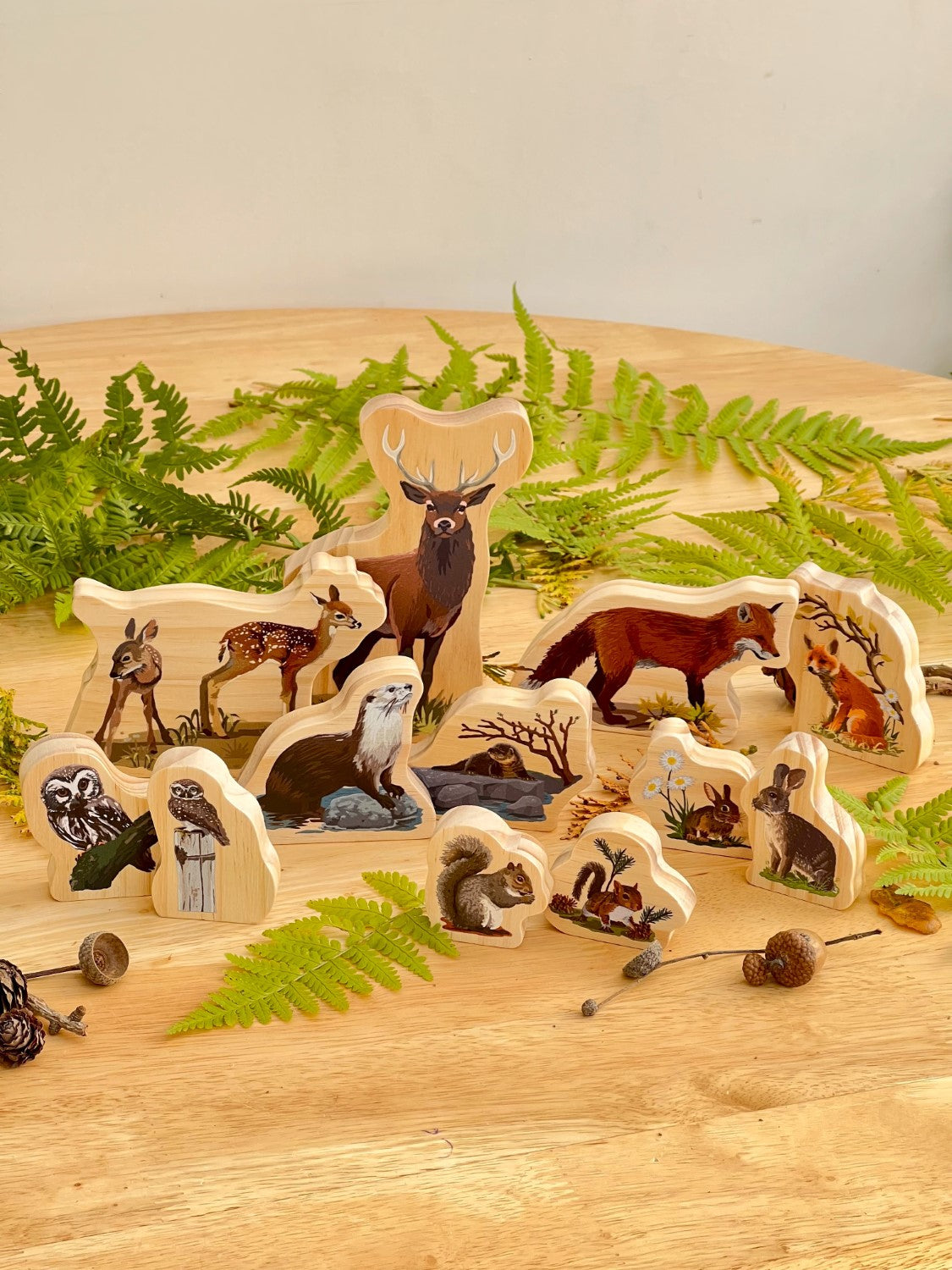 Set of wooden animal figurines on a wooden surface with greenery