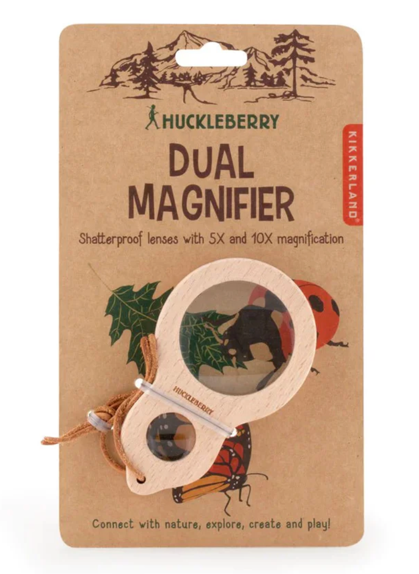 Huckleberry dual magnifier on a kraft paper packaging with nature-themed illustrations.
