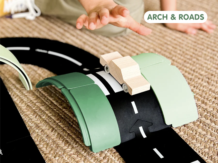 Children's toy set with green arch and black roads on a textured surface