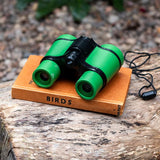 Green binoculars on a book titled 'Birds' on a wooden surface